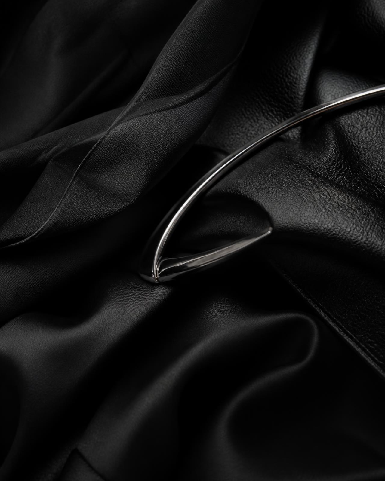 Composição abstrata de couro, seda e organza pretos com acessório metálico